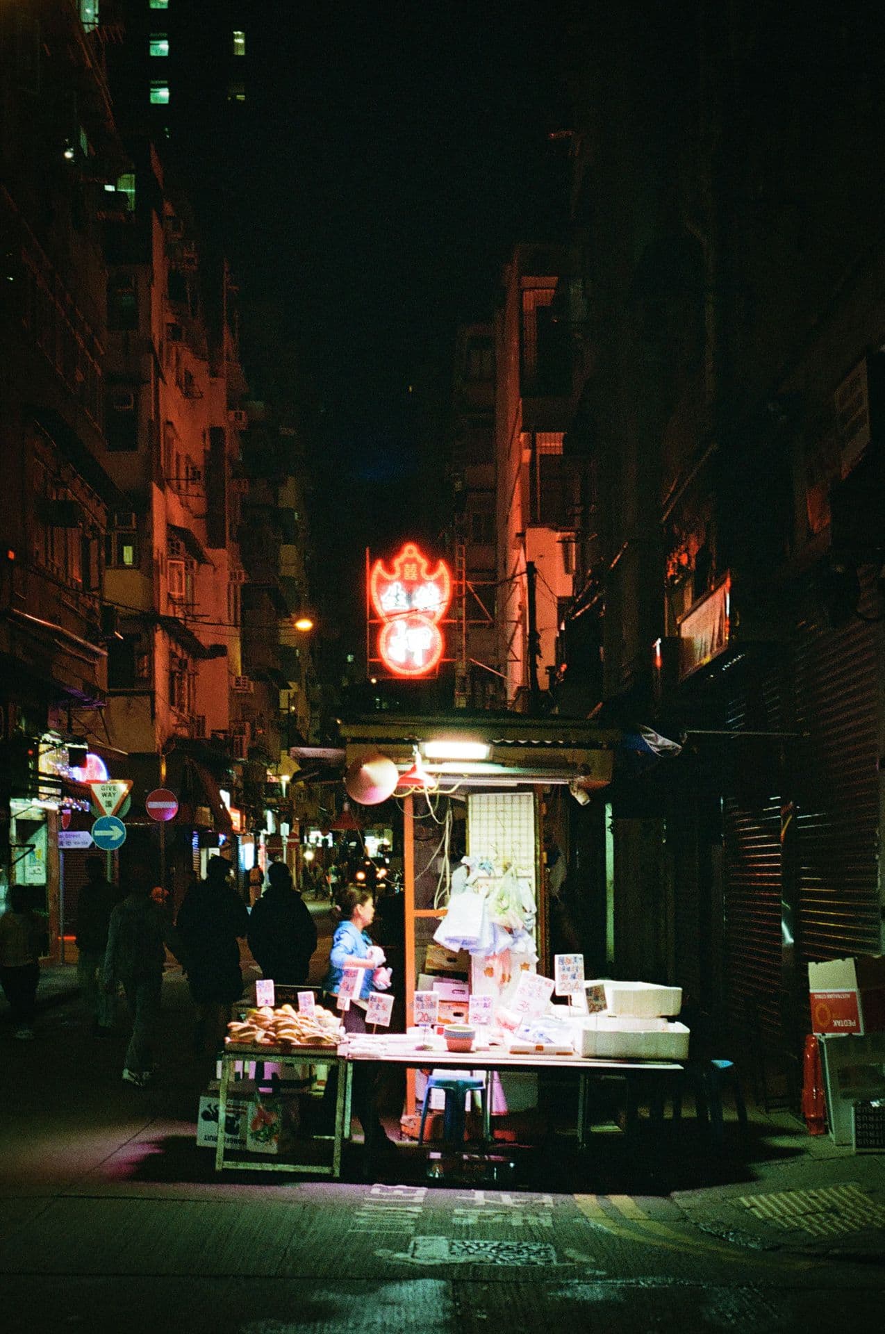 Street vendor in Hong Kong by night with neon sign in the background 35mm film photography