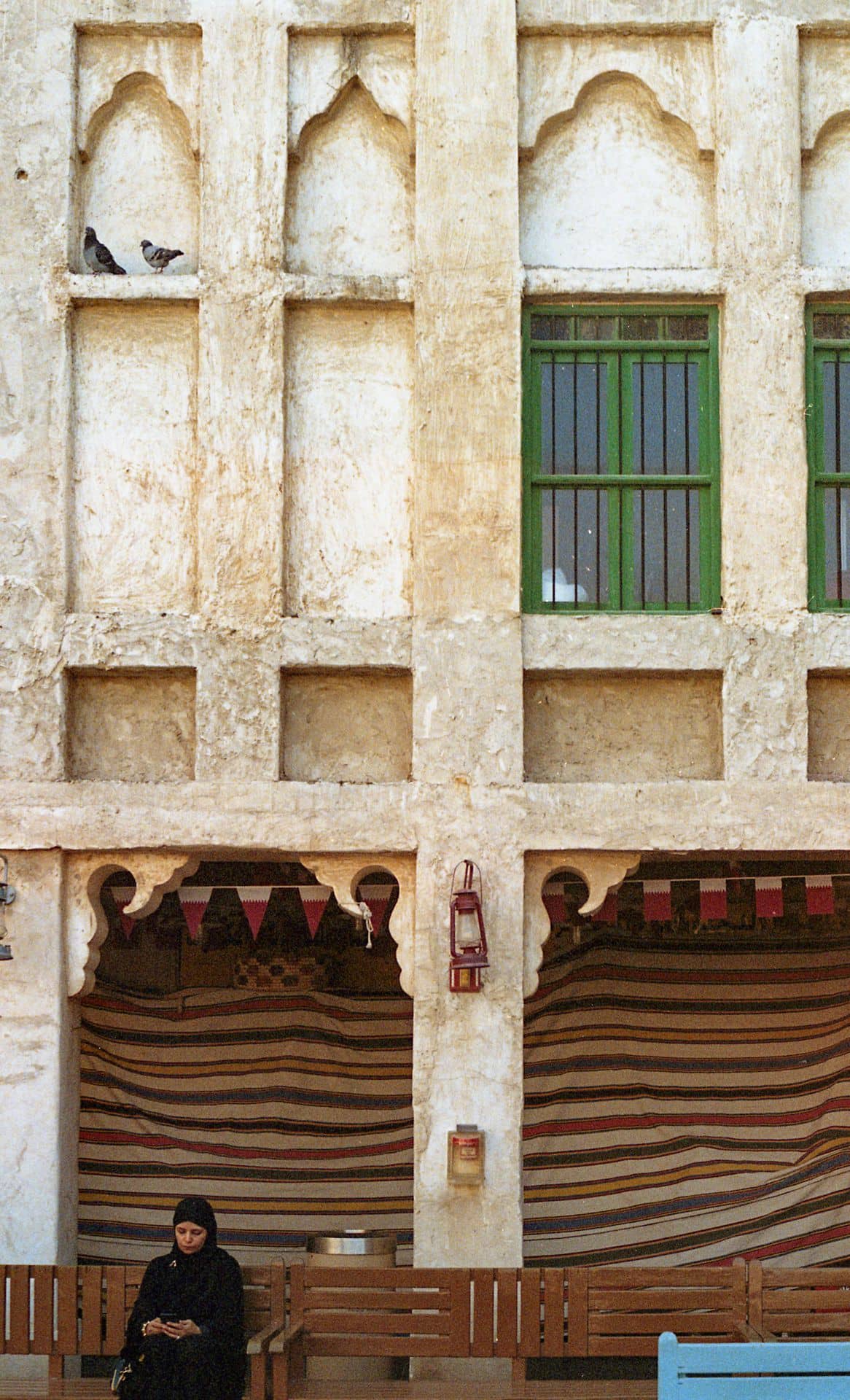 Woman sitting on a bench in front of a wall in Doha Qatar 35mm film photography