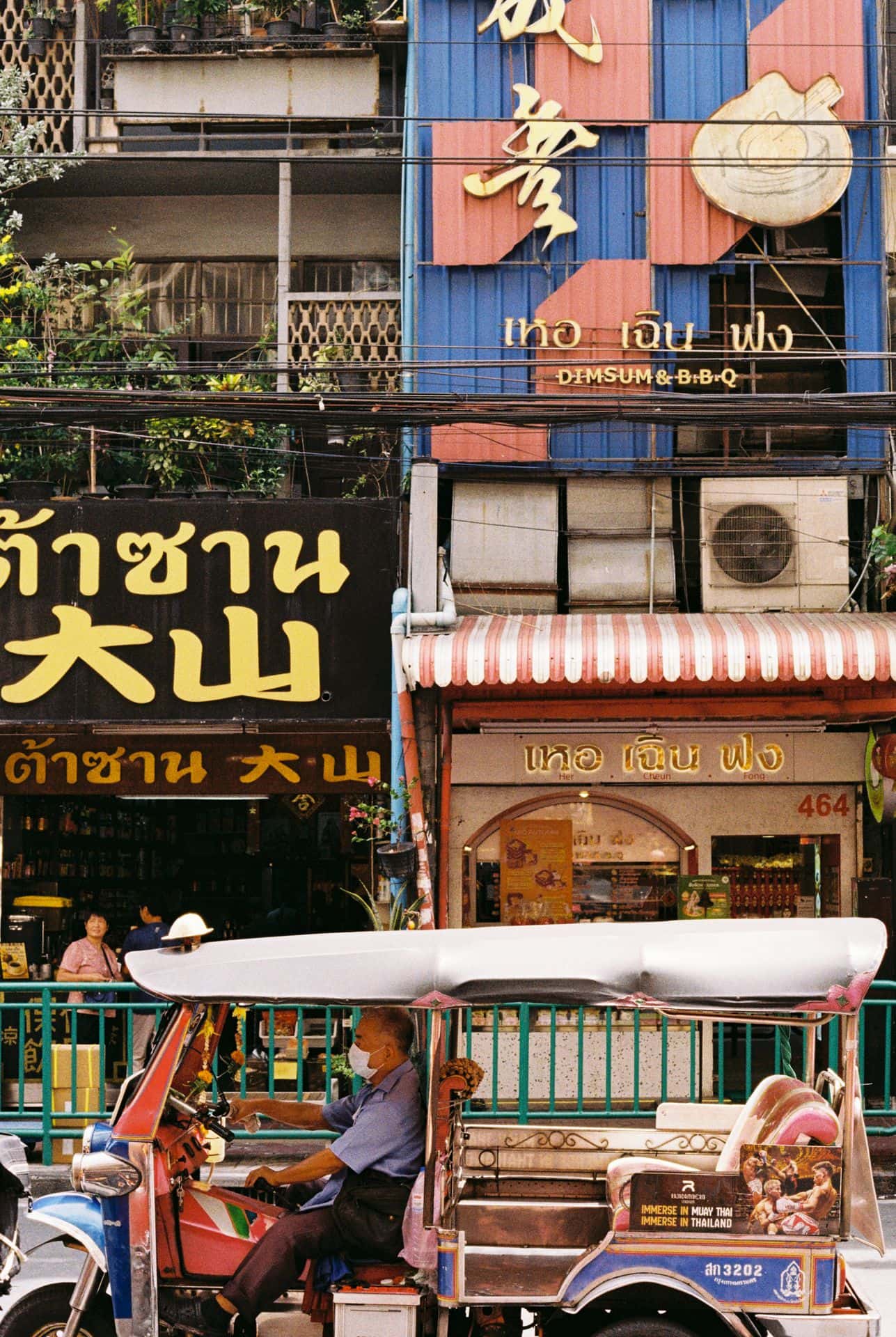 Tuk tuk in front of the vibrant facades in Bangkok Thailand 35mm film photography